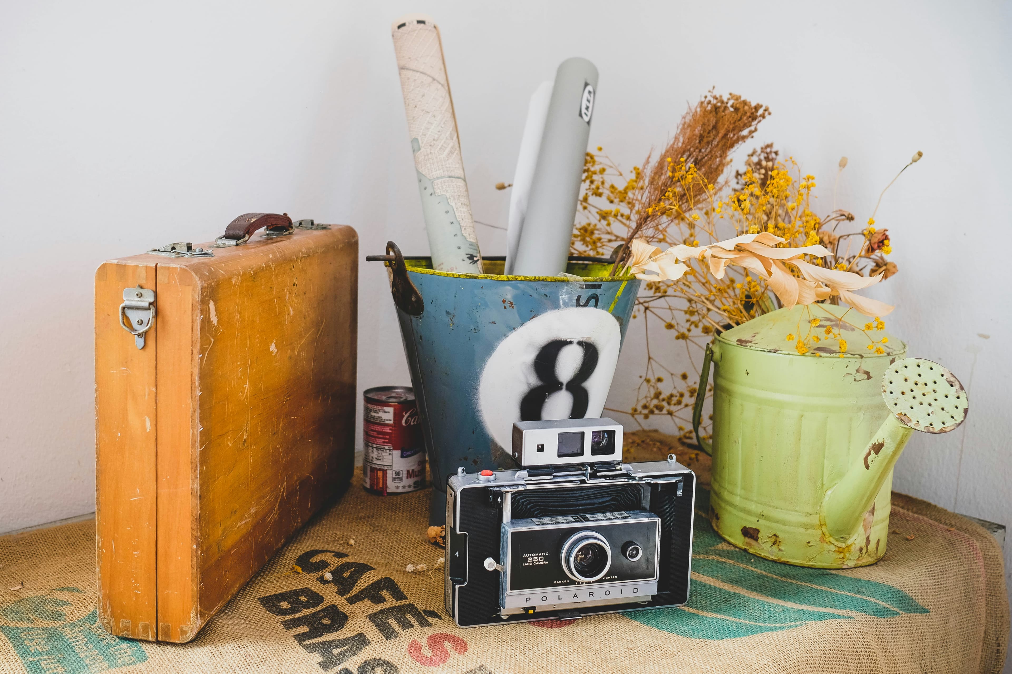A suitcase, camera, watering can, and other donated items ready to drop off